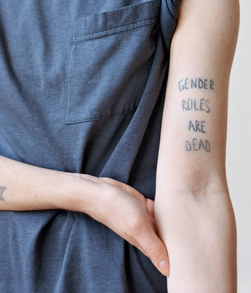 Photo of a person's forearm with a tattoo that reads "Gender Rules Are Dead"
