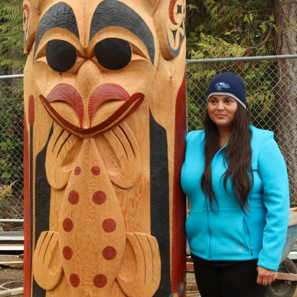 Malynn Foster stands next to a totem pole