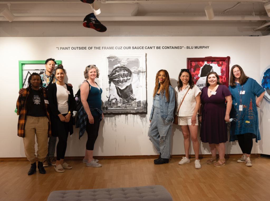A group of 8 people pose for a photo at Blu Murphy's exhibition