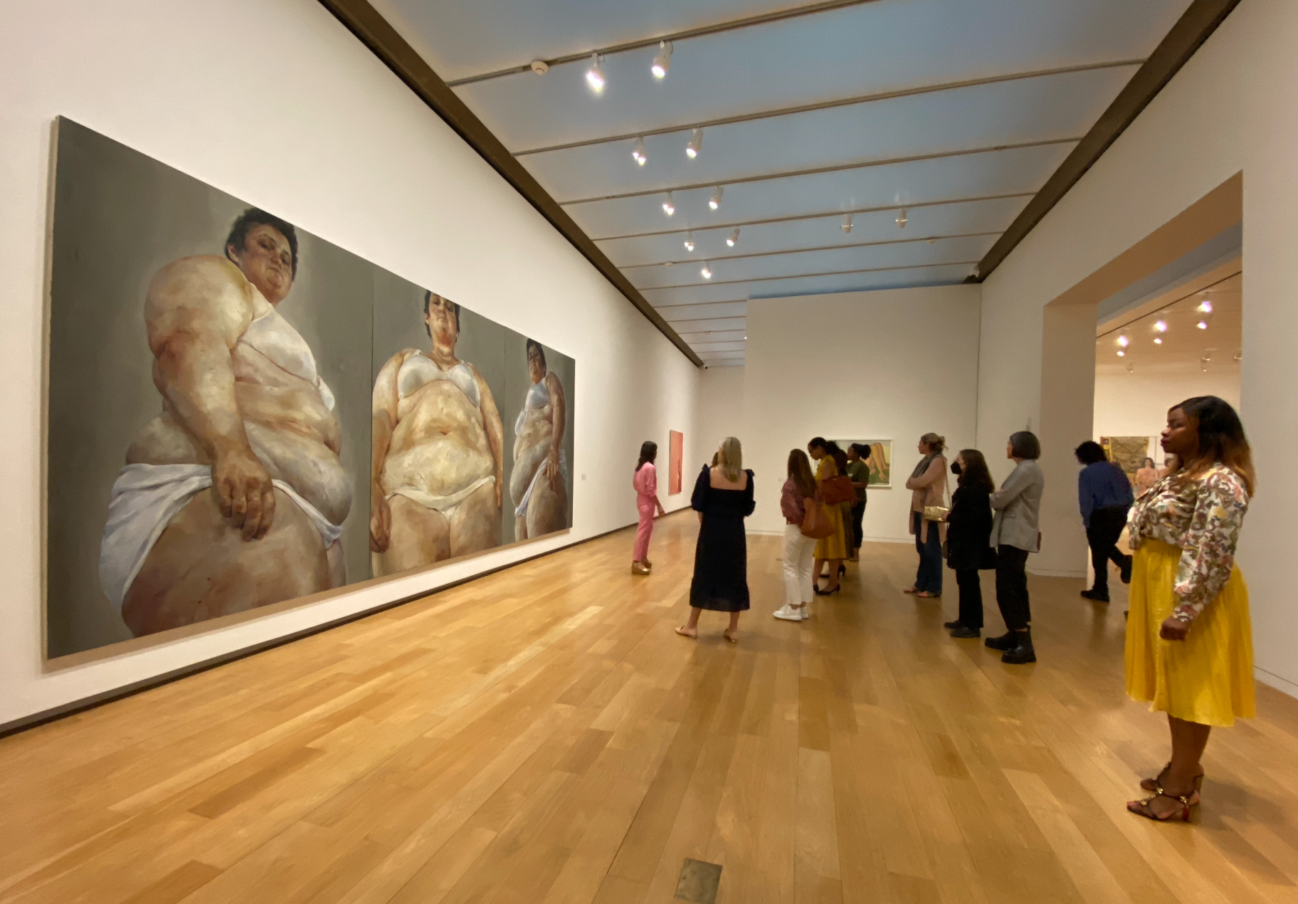 A group faces a large painting by Jenny Saville
